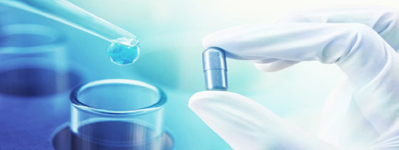 Pharmaceutical research in progress: capsule held by a gloved hand and liquid dropper above lab equipment.